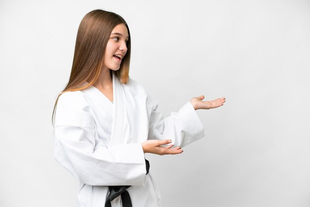 Adolescente faisant du karaté sur fond blanc isolé avec une expression surprise tout en regardant de côté