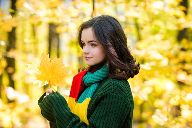 Adolescente avec des feuilles d'automne à la main et érable jaune d'automne