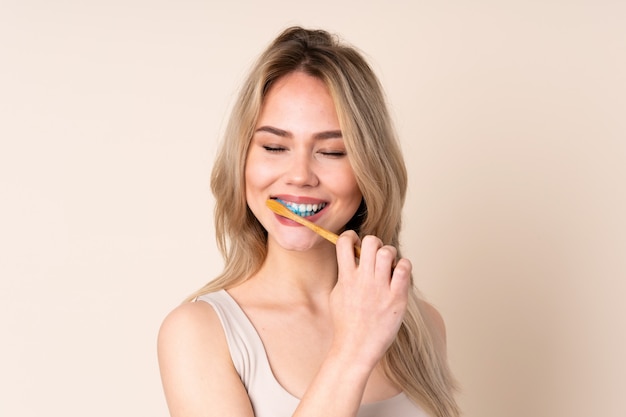 Adolescente fille blonde se brosser les dents sur le mur
