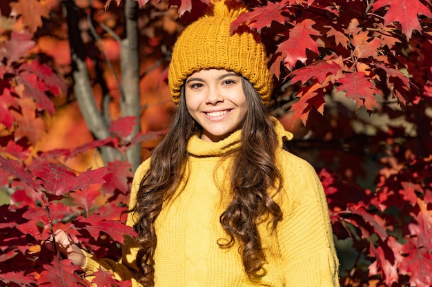 Adolescente sur fond d'automne automne enfant positif au chapeau aux feuilles d'automne sur fond naturel