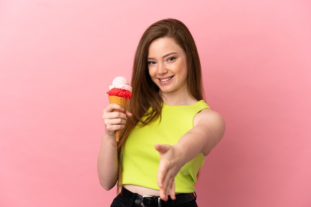 Adolescente avec une glace au cornet sur un mur rose isolé se serrant la main pour conclure une bonne affaire