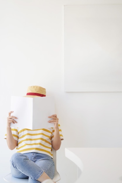 Une adolescente en gros plan tenant et lisant un livre ou un magazine avec un mur blanc dans le concept d'espace de copie