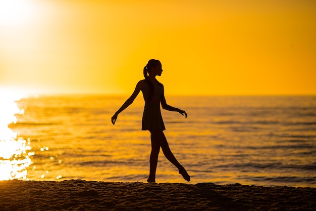 Une adolescente heureuse profite de vacances à la plage tropicale au coucher du soleil