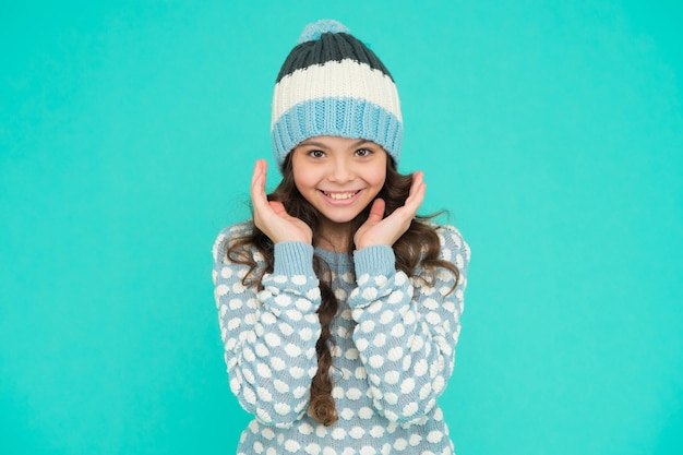 Une adolescente heureuse en pull et chapeau en tricot a de longs cheveux bouclés, des vêtements chauds.