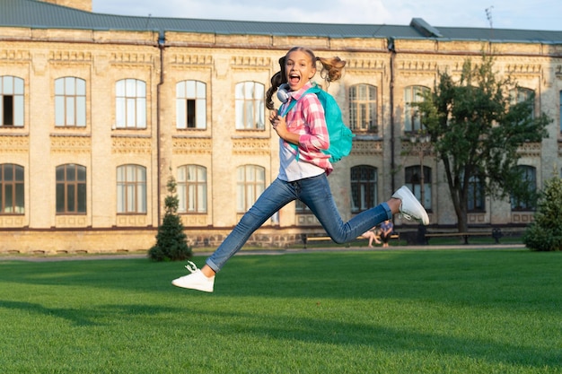 Adolescente heureuse sautant dans la cour de l'école en plein air backtoschool