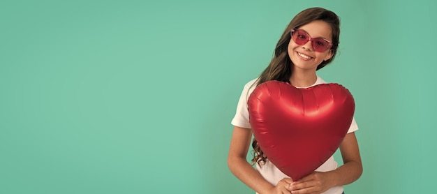 Une adolescente heureuse tient un ballon rouge pour la fête de la Saint-Valentin. Symbole d'amour. Copie l'espace, chérie.