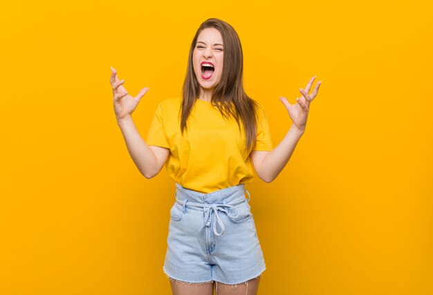 Adolescente jeune femme vêtue d'une chemise jaune hurlant de rage.