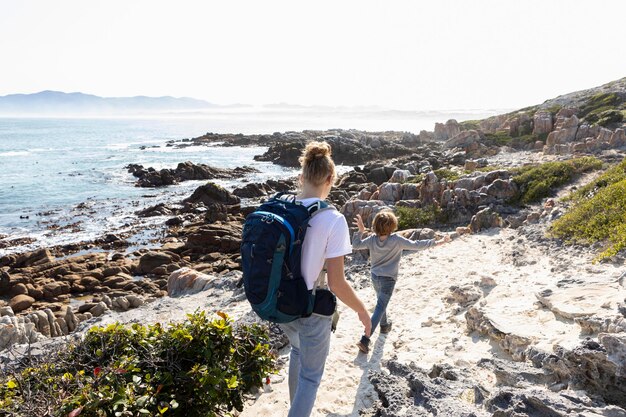 Photo adolescente et jeune frère en randonnée sur un sentier côtier au bord de l'océan