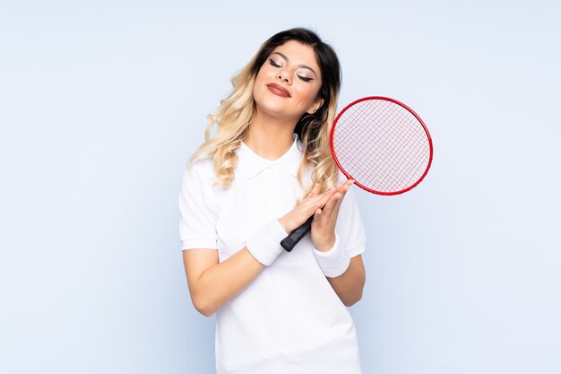 Adolescente jouant au badminton sur le mur bleu applaudissant