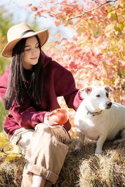 Adolescente jouant avec un chien dans le jardin d'automne