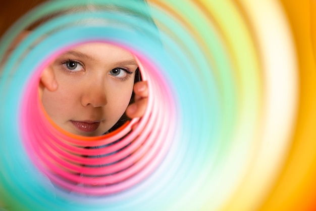 Photo une adolescente joue à un jouet arc-en-ciel sur un fond coloré