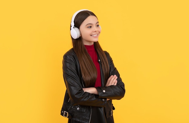 Une adolescente joyeuse écoute de la musique dans des écouteurs sur fond jaune elearning