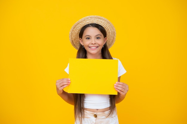 Une adolescente joyeuse tient du papier publicitaire vide avec un espace de copie sur fond jaune