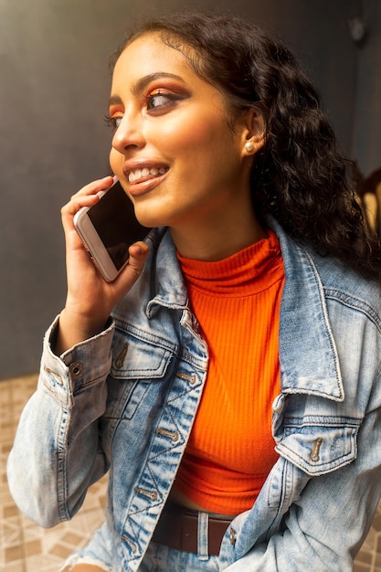 Une adolescente latine bavardant sur son téléphone portable passant un appel téléphonique à l'intérieur