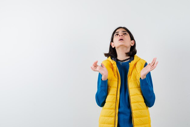 Adolescente levant les yeux et ouvrant ses mains sur fond blanc