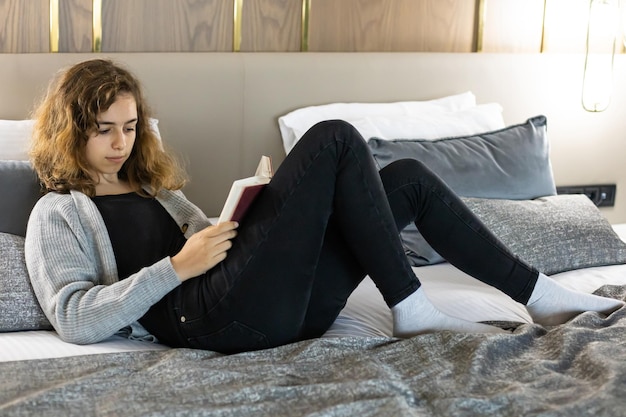 Adolescente lisant un livre sur le lit