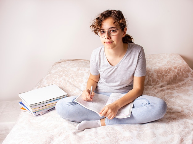 Adolescente sur le lit étudie à la maison en raison de la quarantaine