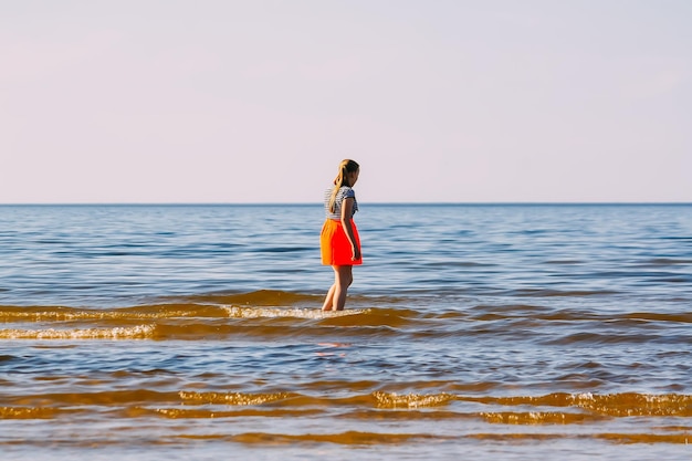 Adolescente marchant au bord de la mer par une chaude journée d'été ensoleillée