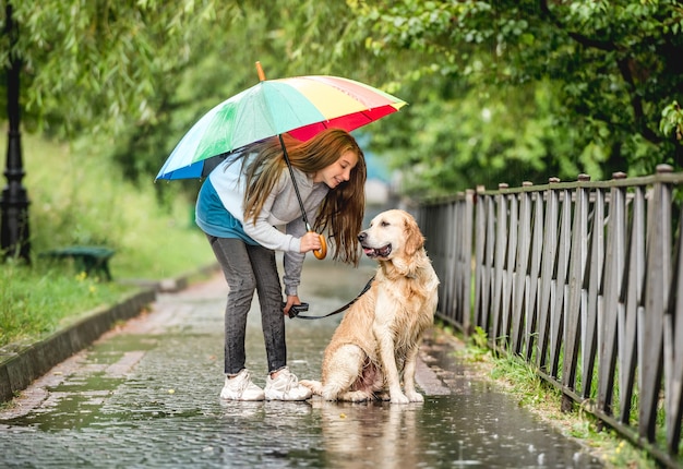 Adolescente marchant avec chien golden retriever au jour de pluie