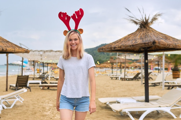 Adolescente marchant sur la plage à Noël avec des oreilles de cerf