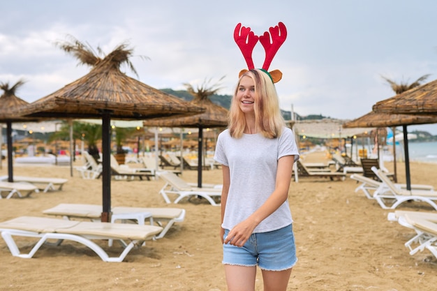 Adolescente marchant sur la plage à Noël avec des oreilles de cerf