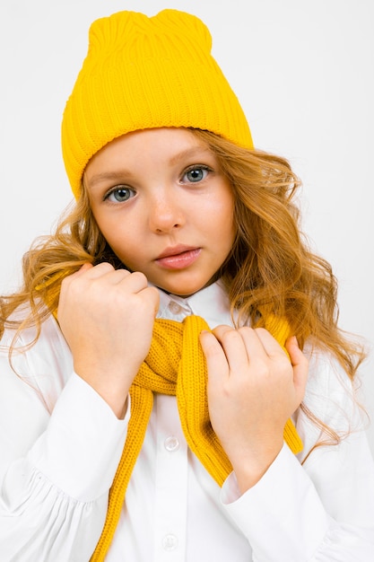 Adolescente mignonne dans un chapeau jaune avec un foulard sur gros plan blanc