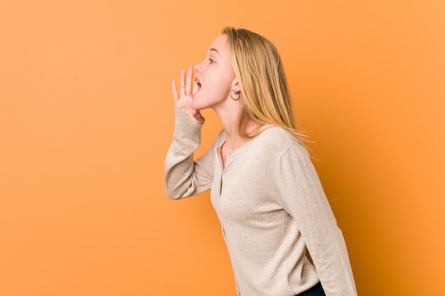 Adolescente mignonne et naturelle femme criant et tenant la paume près de la bouche ouverte.