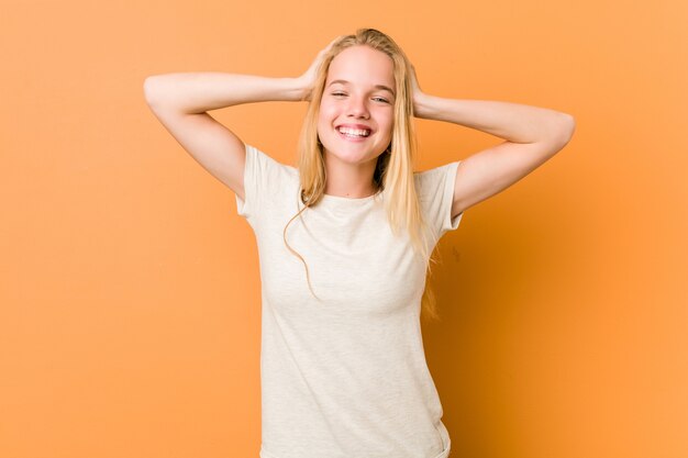 Adolescente mignonne et naturelle rit joyeusement en gardant les mains sur la tête. Concept de bonheur.