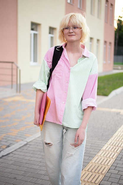 Photo adolescente mignonne avec sac à dos marchant près de l'écolephotographie verticale