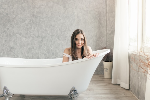 Adolescente mignonne souriante attendant dans la baignoire