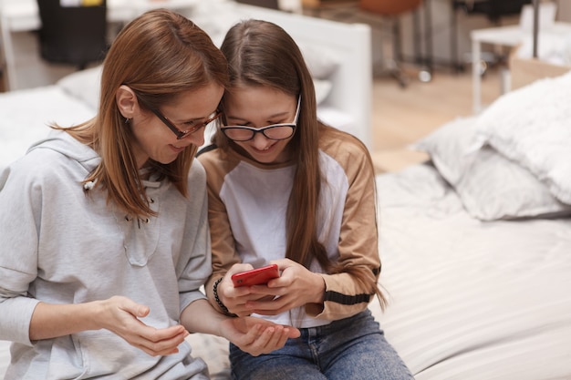 Une adolescente montrant quelque chose sur son téléphone intelligent à sa mère