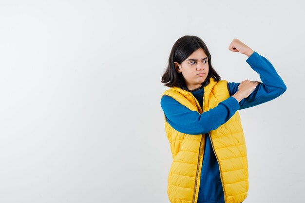 Adolescente montrant ses muscles sur fond blanc