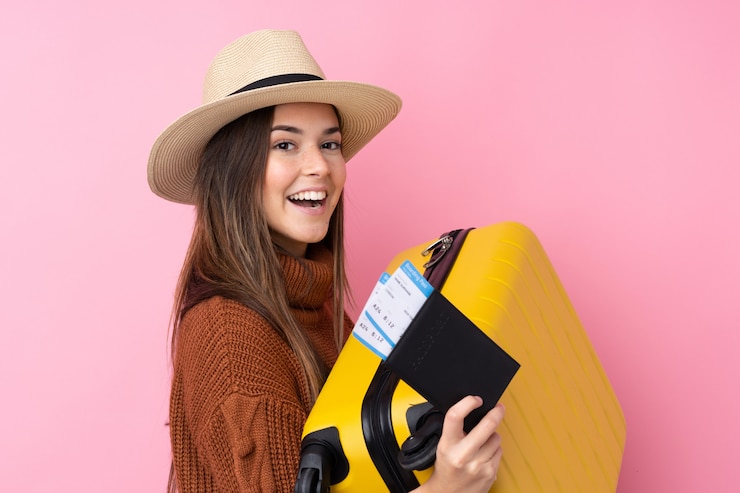 Photo adolescente sur mur rose isolé en vacances avec valise et passeport