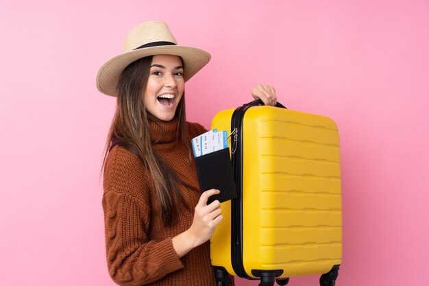 Adolescente sur mur rose isolé en vacances avec valise et passeport