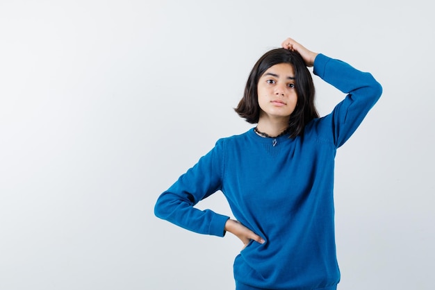 L'adolescente pense en mettant sa main sur la taille sur fond blanc