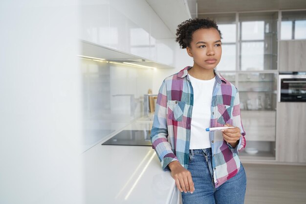 Une adolescente pensive obtient un résultat de test de grossesse positif Grossesse et maternité non désirées