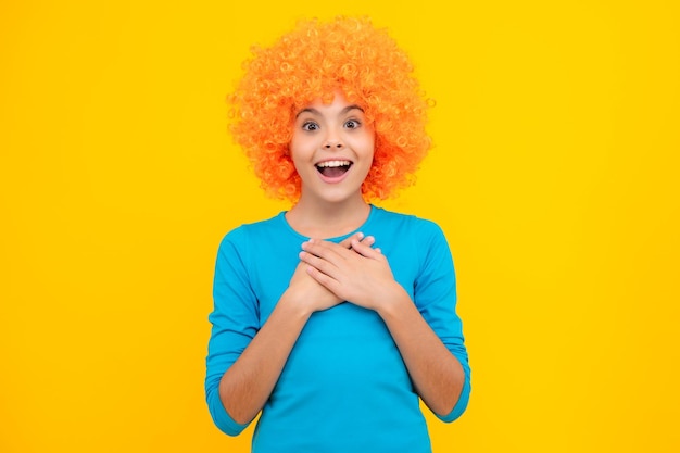 Adolescente avec perruque jaune drôle d'enfant portant des cheveux perruque frisée orange excité adolescent heureux étonné et ravi d'émotions