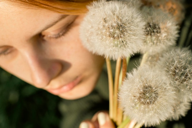 Adolescente avec des pissenlits au printemps