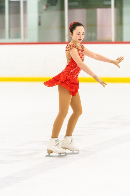 Adolescente pratiquant le patinage artistique sur une patinoire intérieure.