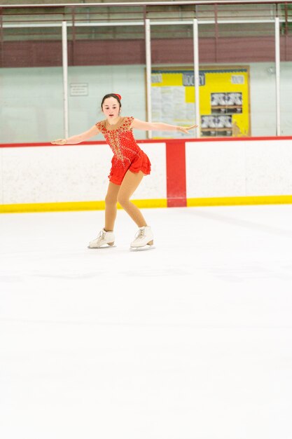 Adolescente pratiquant le patinage artistique sur une patinoire intérieure.