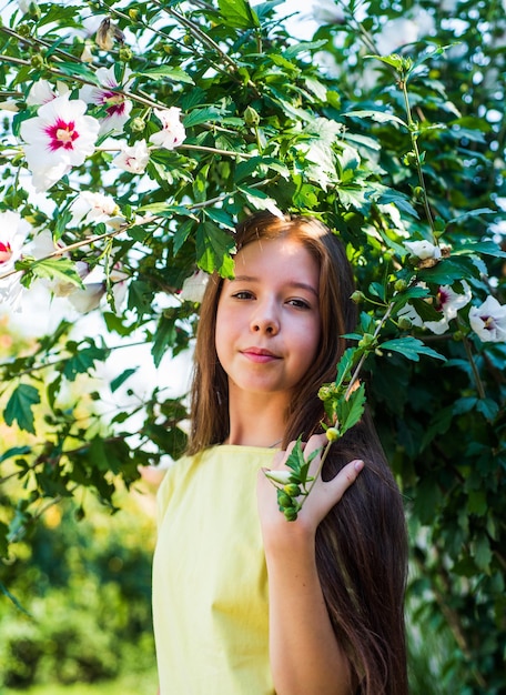 Adolescente près de l'hibiscus en fleurs enfant à l'arbre en fleurs enfant profitez de la fleur de brousse