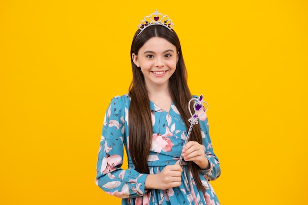 Adolescente princesse fille enfant sur fond jaune histoire du pays des merveilles romantique petite fée fille avec couronne et baguette magique mettant le sort