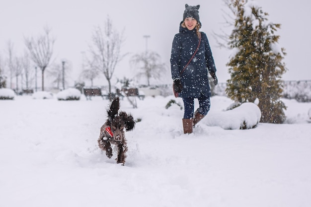 Une adolescente promener son chien à l'extérieur en hiver l'épagneul russe s'exécute avec des oreilles battantes dans la neige et joue