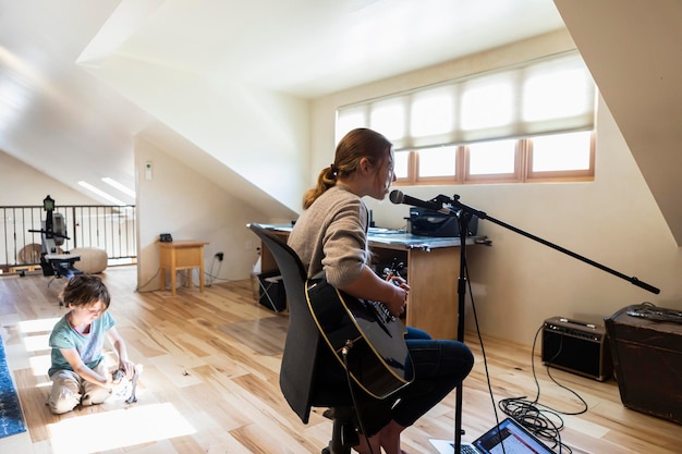 Photo adolescente de quatorze ans jouant de la guitare et chantant son frère jouant en arrière-plan