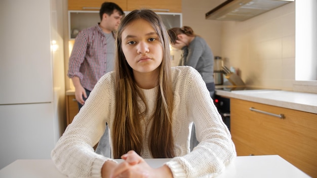 Photo adolescente regardant à huis clos pendant que les parents se disputent et ont des conflits dans la cuisine