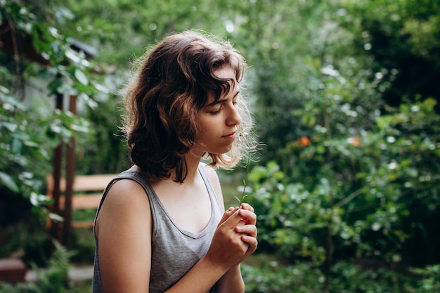 Adolescente reniflant une fleur de camomille dans la forêt. Beauté naturelle. Des moments francs