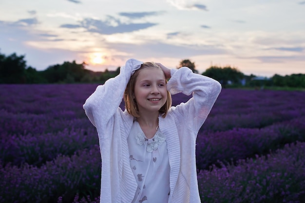 Adolescente rêveuse se promène parmi les fleurs violettes lors de belles vacances de voyage d'été au coucher du soleil