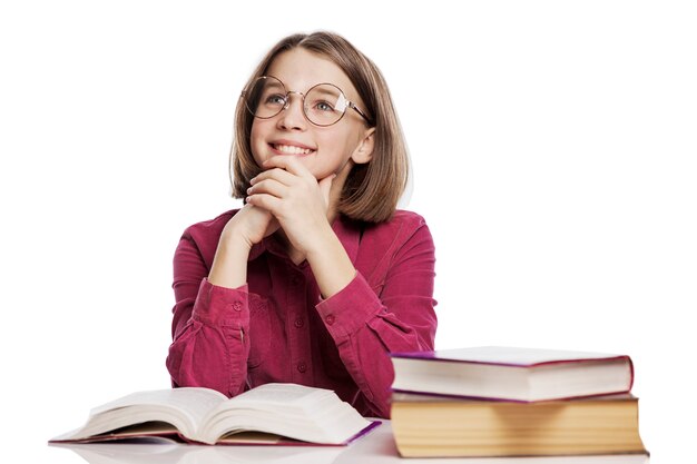 Adolescente rire dans des verres est assis à une table avec des livres. Connaissances et éducation. .