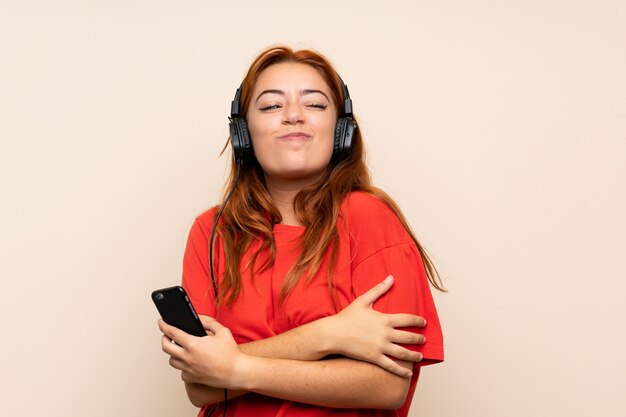 Adolescente rousse écoute de la musique avec un téléphone portable