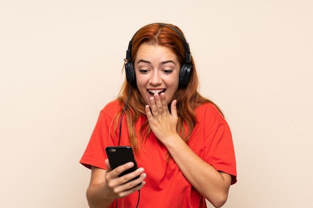 Adolescente rousse écoute de la musique avec un téléphone portable